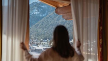 A woman is enjoying the view on the village in winter from one of the rooms