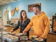 A couple is serving themselves at the breakfast buffet